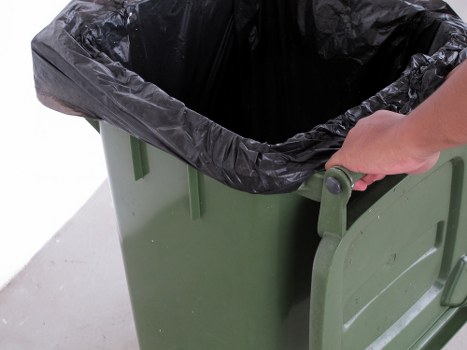 Worker wearing high-visibility PPE positioning a skip with cones and signage